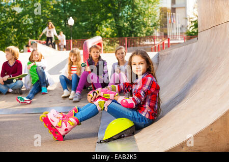 Girl wears in-line skates sits in front with mates Stock Photo