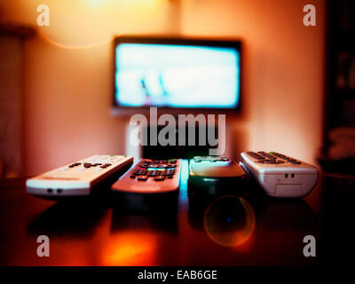 Four remote control devices and tv Stock Photo