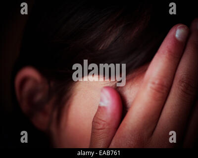 Girl hides face in hands Stock Photo