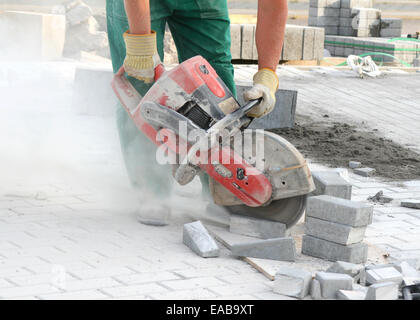 Close look at the worker with concrete saw in his hands and working in dusty conditions Stock Photo