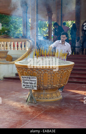 Cambodia, Siem Reap.  Worshiper Placing Incense at Preah Ang Chek and Preah Ang Chorm Temple. Stock Photo