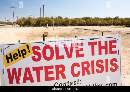 A farmers sign about the water crisis next to a farmers dried up waterhole, folllowing a 4 year long drought, near Bakersfield in the Central Valley, California, USA, with the soil turned to dust. The whole of California is in a catastrophic drought with $2.2 Billion annually lost from the agricultural sector, with many workers laid off. One third of children in California currently go to bed hungry. 428,000 acres of farmland have been taken out of production in the Central Valley due to the drought. Stock Photo