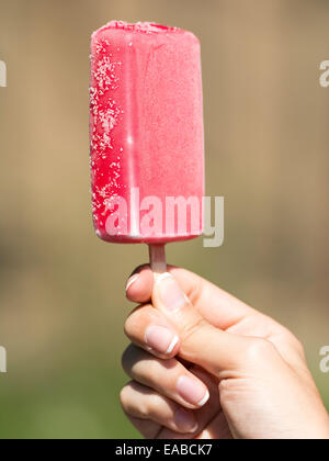 Girl Hand Holding Pink Ice Cream On Stick Stock Photo