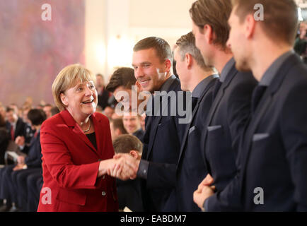 Berlin, Germany. 10th Nov, 2014. German Chancellor Angela Merkel greets national team soccer players Lukas Podolski (l-r) and Bastian Schweinsteiger at Bellevue Castle in Berlin, Germany, 10 November 2014. The German national team is honored with the award 'Silbernes Lorbeerblatt' for winning the 2014 world cup in Brazil. PHOTO: WOLFGANG KUMM/dpa/Alamy Live News Stock Photo