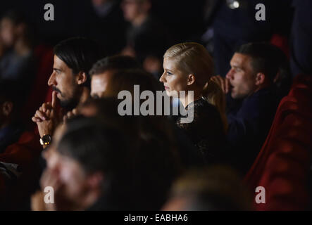 Sony Center, Potsdamer Platz, Berlin, Germany. 10th Nov, 2014. Germany's Sami Khedira (L-R), his girlfriend Lena Gercke and Lukas Podolski attend the world premiere of the film 'Die Mannschaft' (lit. 'The team') at the Cinestar movie theater at Sony Center, Potsdamer Platz, Berlin, Germany, 10 November 2014. Bastian Schweinsteiger (L) and former captain Philipp Lahm (R) hold the trophy in the first row, Mesut Oezil and Mario Goetze stand to their right. The film is the official documentary of the FIFA Soccer World Championship 2014 in Brazil. PHOTO: JENS KALAENE/dpa/Alamy Live News Stock Photo