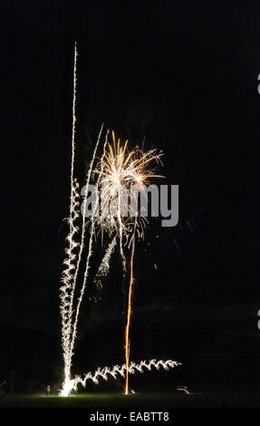 Man launching fireworks at a village firework display, with one rocket going dangerously sideways (UK) Stock Photo