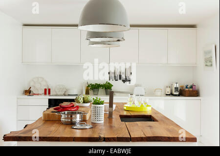 Three industrial lamps above elm-topped kitchen island unit Stock Photo