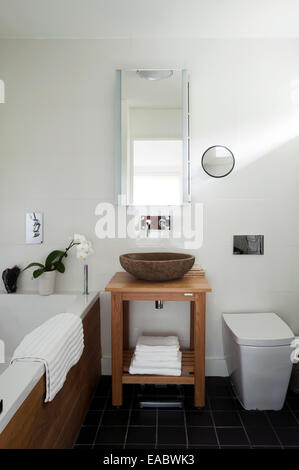 Stone bowl washbasin with wood stand in bathroom with slate floor tiles Stock Photo