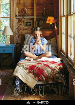 girl on bed doing cats cradle in country cabin Stock Photo