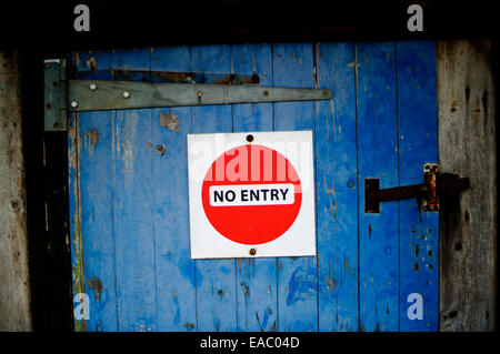 Red 'No Entry' sign on a rustic old blue wooden door. Stock Photo