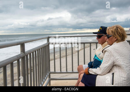A retired couple sit on the boardwalk by the sea in Ocean City, New Jersey USA Stock Photo