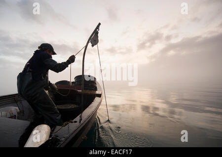 Commercial halibut fishing by hand using longline gear out of an open skiff in Kachemak Bay, Kenai Peninsula; Alaska, USA Stock Photo