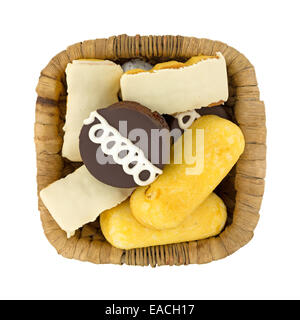 Top view of junk food including powdered donuts, cream filled cakes, chocolate iced cakes and iced covered cakes in a wicker bas Stock Photo