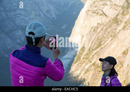 Tourists at dusk on Glacier Point above Yosemite Valley, California, USA looking towards Half Dome. Stock Photo