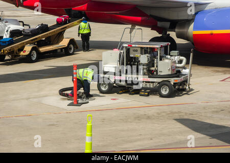 Airport handler loading baggage being put on a conveyor into a plane at Beziers Cap d&#39;Agde ...