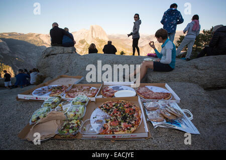 Tourists picnicing on Glacier Point overlooking Half Dome and the Yosemite Valley, California, USA. Stock Photo