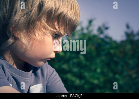 pensive boy looking down (6 years), France. Stock Photo