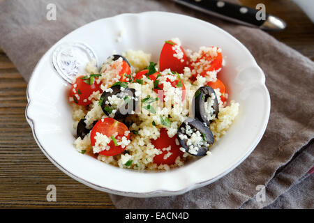 Delicious salad couscous with vegetables and olives on a plate, close up Stock Photo