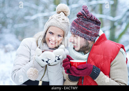 Happy couple laughing together with hot tea in winter Stock Photo