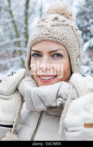 Smiling woman standing with wool cap in winter snow Stock Photo