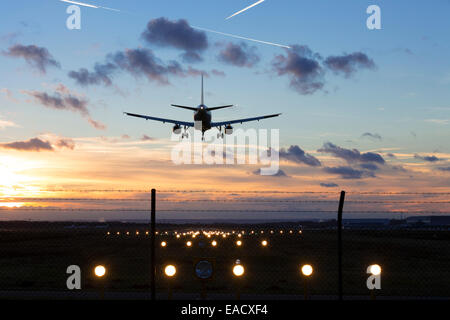 Airplane during the landing approach, crosswind runway with position lights, runway of Cologne-Bonn Airport at sunset, Cologne Stock Photo