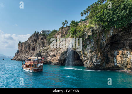 Excursion boat in the Gulf of Antalya, cliffs with waterfall, Yavuz Özcan Park at the top, Antalya, Turkish Adriatic, Turkey Stock Photo