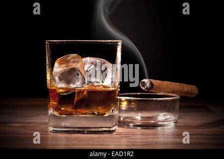 Whiskey drink with smoking cigar on wooden table Stock Photo