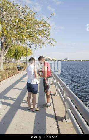 African American man signing a paper handed to him by a caucasian woan on the riverwalk at Rossi Park in Bradenton, Florida, USA Stock Photo