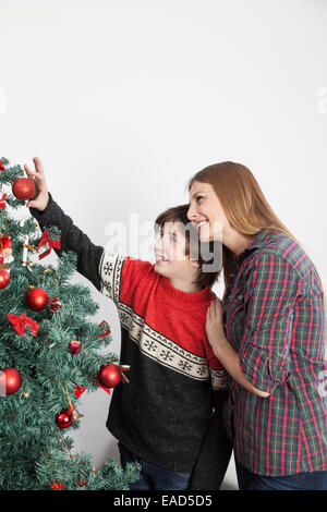 Mom with her son putting ornaments on the christmas tree Stock Photo