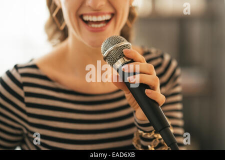 Closeup on young woman singing with microphone in loft apartment Stock Photo