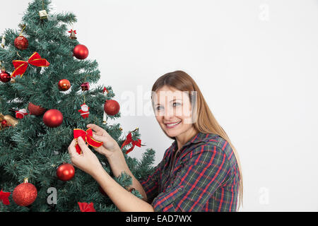 Woman putting a bow in the christmas tree Stock Photo