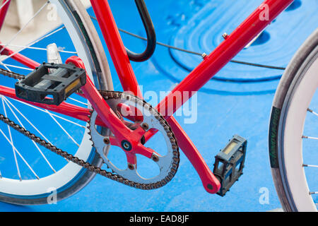 Close up of red bicycle pedals and chain contrasting with blue background Stock Photo