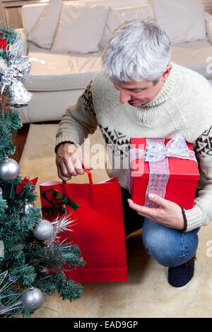 Man putting the gift under the christmas tree Stock Photo