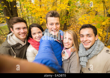 group of smiling men and women in autumn park Stock Photo