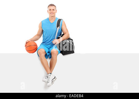 Basketball player sitting on a blank panel isolated on white background Stock Photo