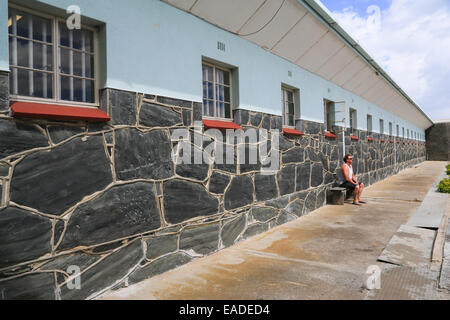 A tourist sitting on a bench outside the prison cell occupied by Nelson Mandela at Robben Island, South Africa. Stock Photo