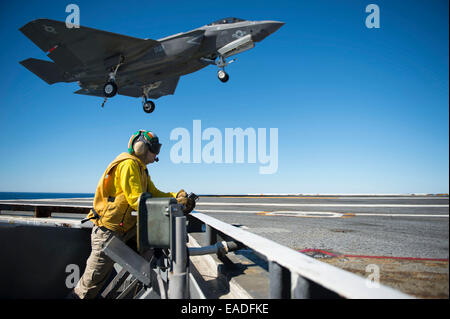 A US Navy flight crew watches a F-35C Lightning II joint strike fighter conduct and arrested landing on the flight deck of the aircraft carrier USS Nimitz November 6, 2014 in the Pacific Ocean. Stock Photo