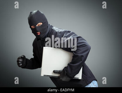 Thief stealing laptop computer Stock Photo