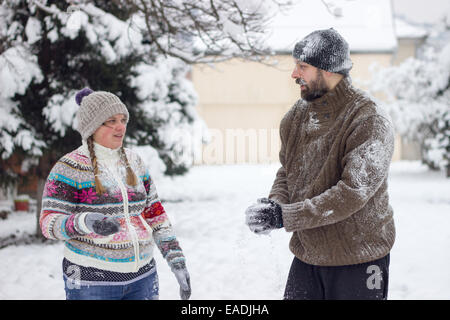 Cute young hipster couple covered in snow in the middle of a snowball fight Stock Photo