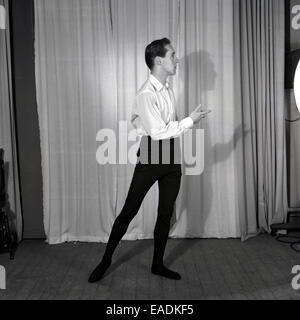 1950s, Historical picture of a slim male ballet dancer practising his moves on stage in front of a curtain. Stock Photo