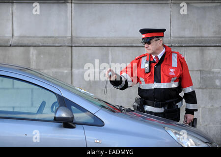 A traffic warden photographs a car after issuing a parking ticket for illegal parking. Stock Photo