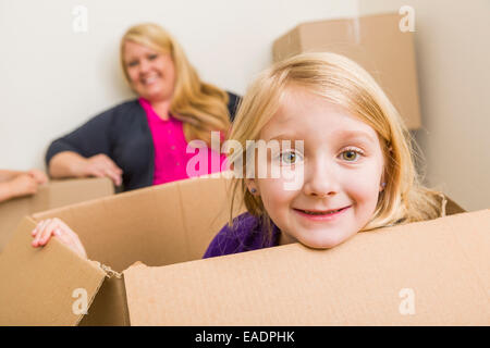 Happy Young Mother and Daughter Having Fun With Moving Boxes. Stock Photo