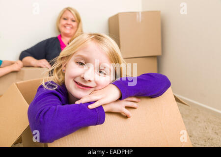 Happy Young Mother and Daughter Having Fun With Moving Boxes. Stock Photo