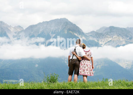 Man and a woman wearing traditional costume looking towards the mountains, Aldrans, Tyrol, Austria Stock Photo