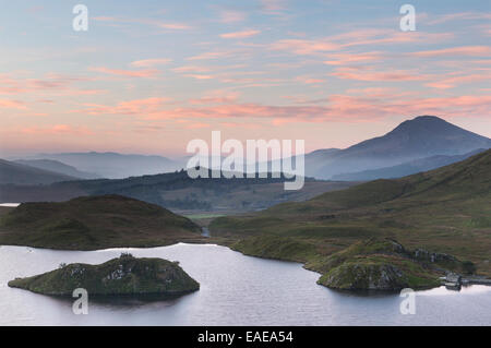 A beautiful sky glows above Llyn Dywarchen, Snowdonia, at dawn just before sunrise. Stock Photo