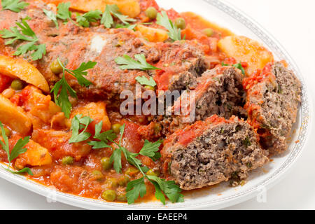 Homemade meatloaf baked in tomato sauce with peas and potatoes. Stock Photo