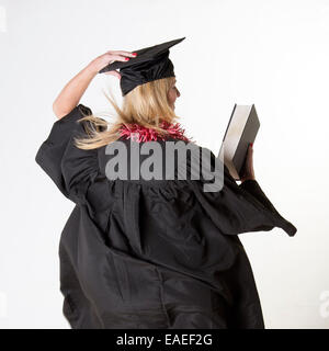Female graduate student in a black graduation gown holding a diploma ...
