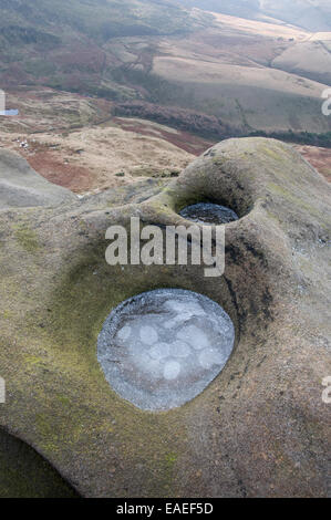 Small round pools of frozen water in gritstone rocks on the edge of the Kinder Scout plateau. Stock Photo