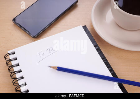 to-do list with note pad, pencil, mobile phone and cup of coffee on desk Stock Photo