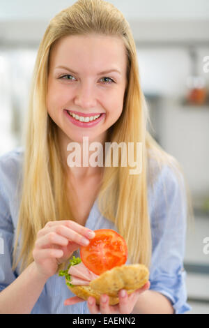 Smiling young woman making sandwich Stock Photo
